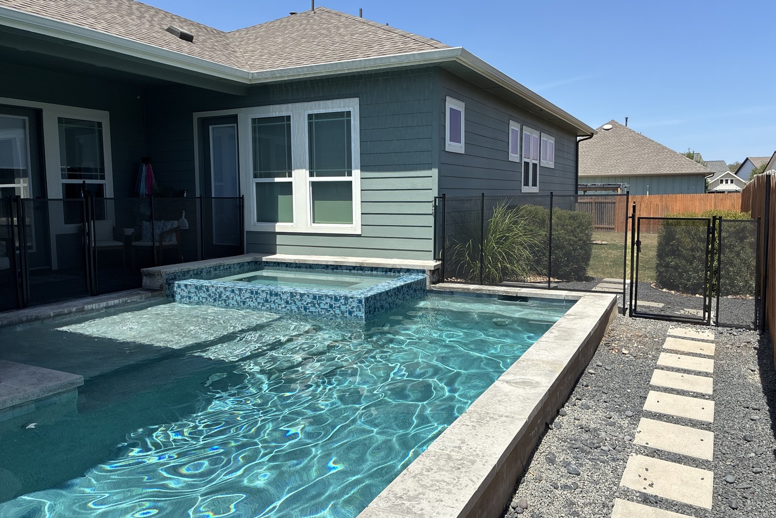 Removable mesh pool fence with a self-closing safety gate around a modern pool and spa in the Easton Park neighborhood of Austin TX, All-Safe certified