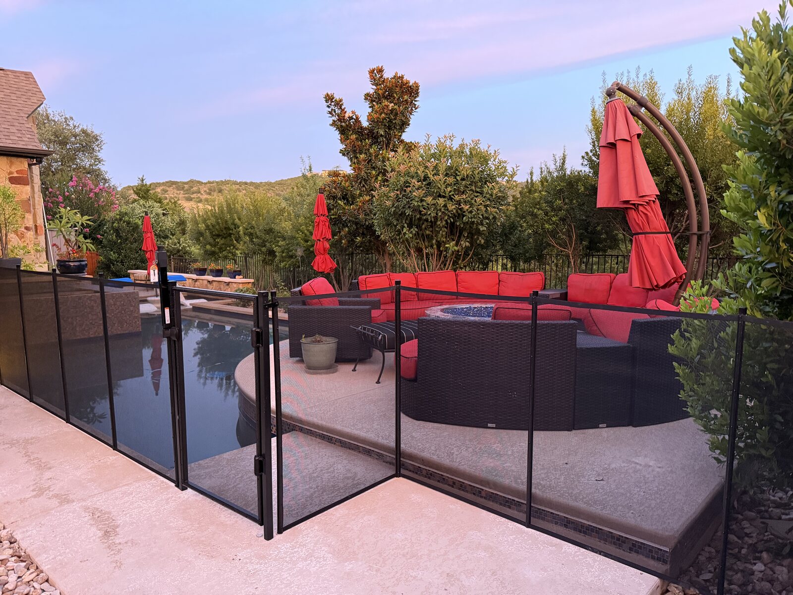 Removable mesh pool fence around a pool, spa, and patio at golden hour in Bee Cave TX, All-Safe certified