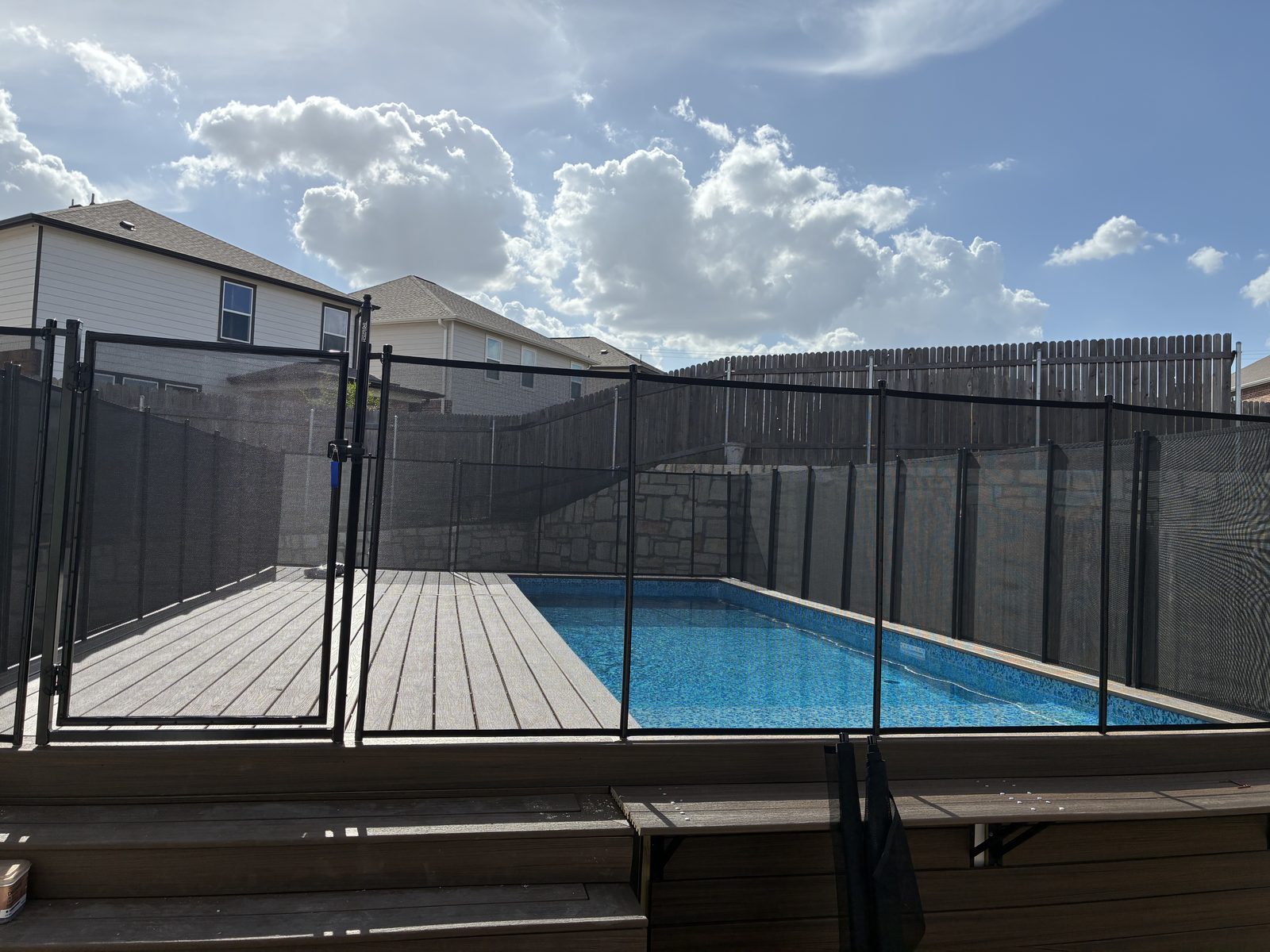 Removable mesh pool fence with a self-closing gate around a raised pool deck in Pflugerville TX