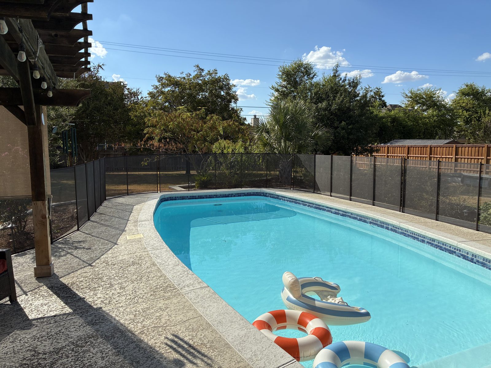 Removable mesh pool fence following the curve of a pool deck in a Round Rock TX backyard
