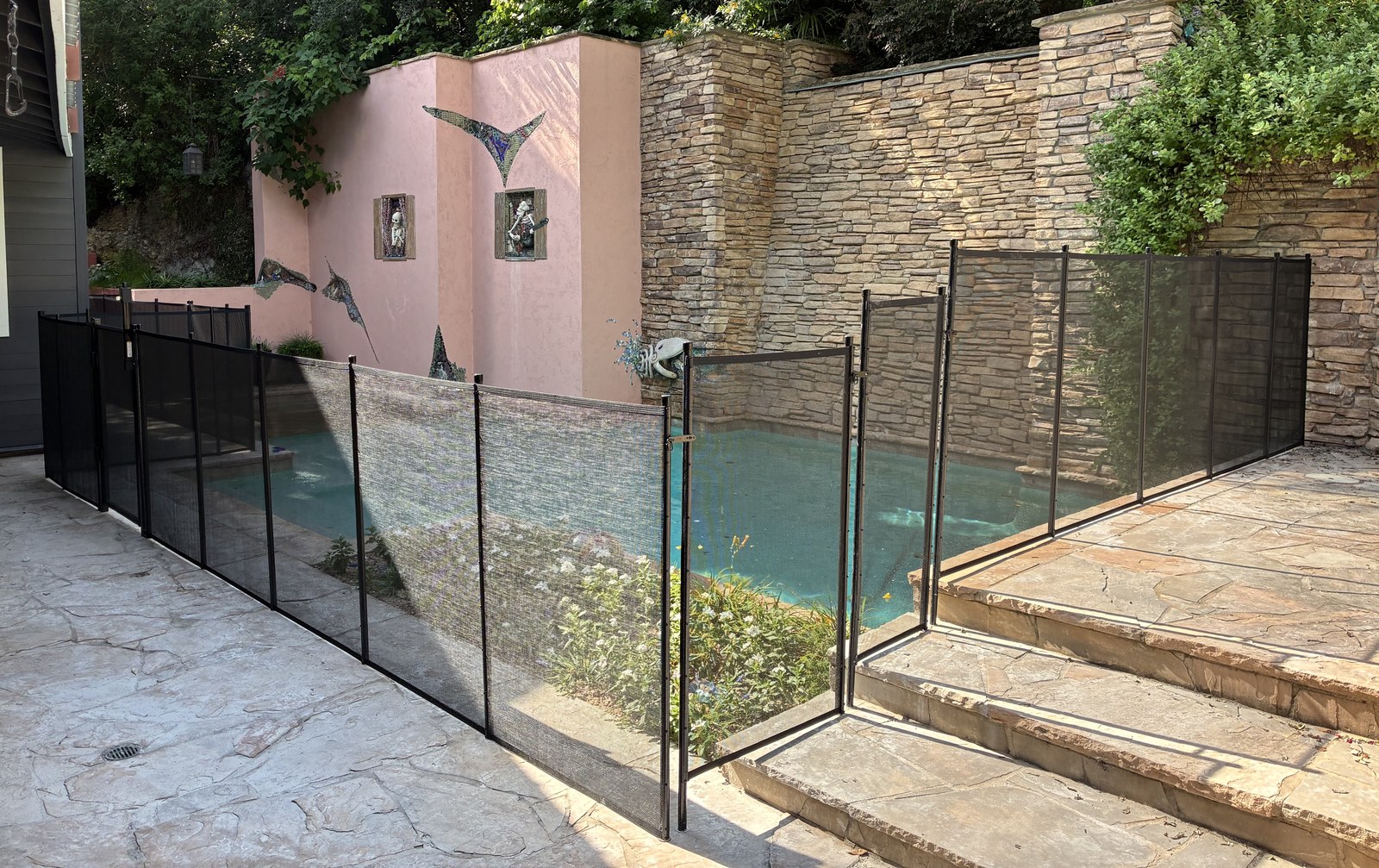 Removable mesh pool fence with self-latching gate following flagstone steps around a designer pool near Austin, All-Safe certified